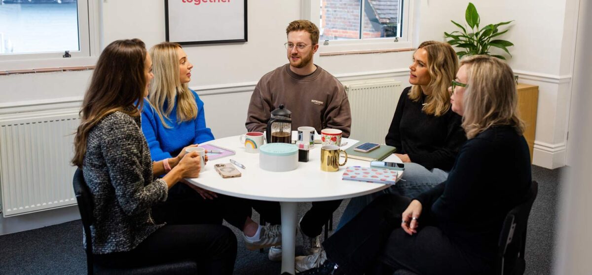 Marketing agency team gathered around a table for a collaborative strategy discussion