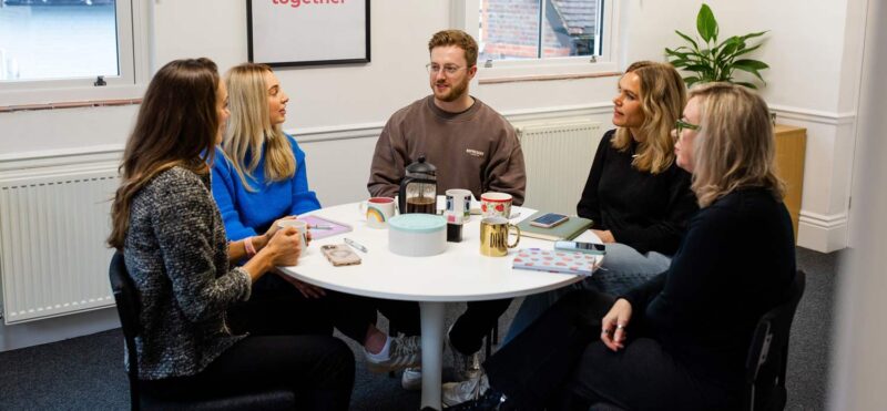 Marketing agency team gathered around a table for a collaborative strategy discussion