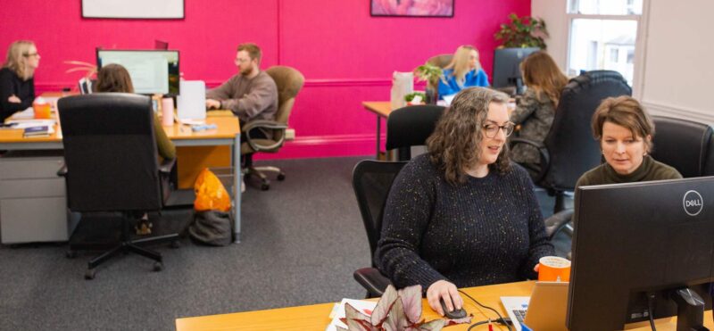 Marketing agency team collaborating at desks in a modern open plan office