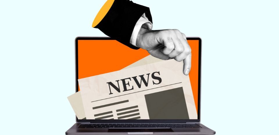 quirky image of a hand wearing a suit jacket and long sleeve shirt picking a newspaper out of a laptop screen