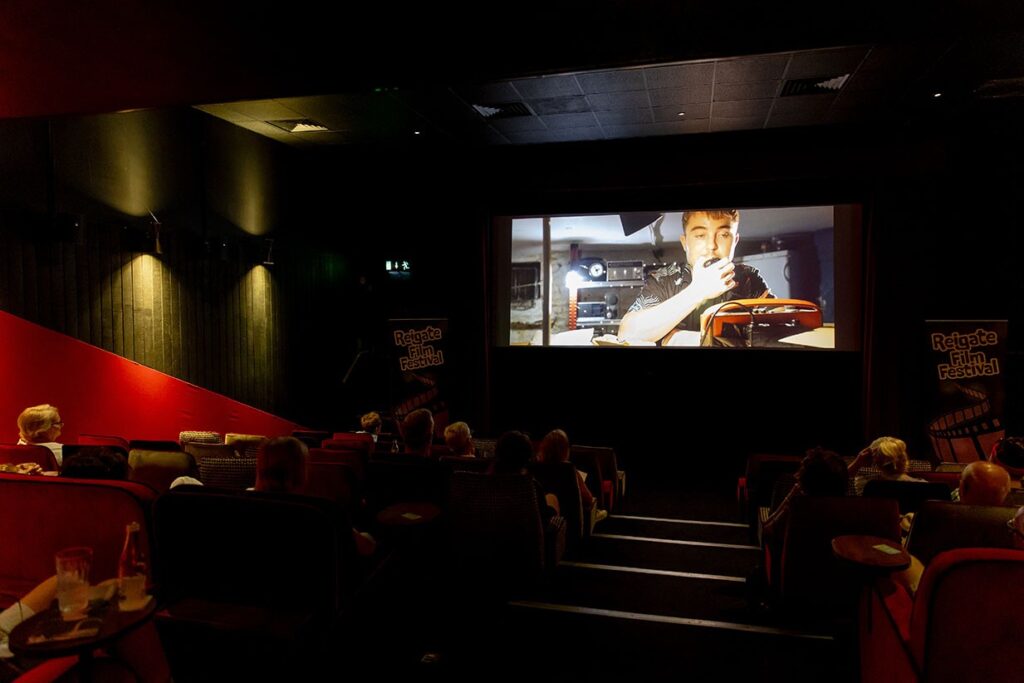 Film screening at Everyman Cinema as part of Reigate Summer Festival. Picture shows a dark cinema room with a film playing. 