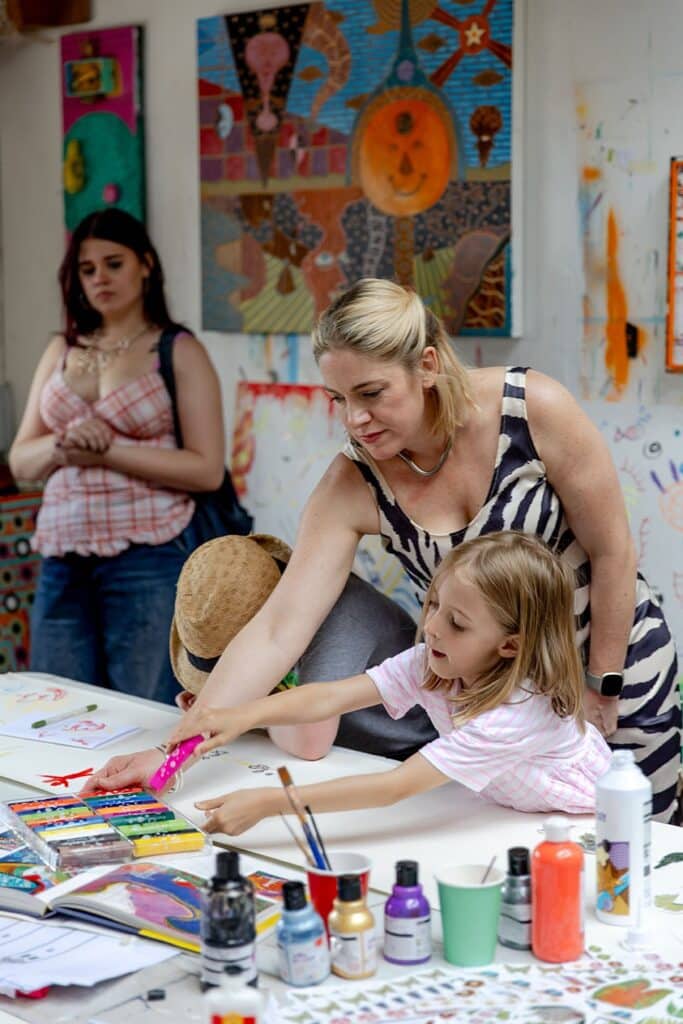 A child and an adult are pictured painting together. Arts & crafts at Reigate Summer Festival. 
