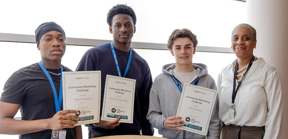 Three smiling boys stand in front of a bright window, holding certificates. Three young men wear lanyards, accompanied by an teacher in a white blouse.